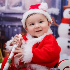 A sweet smile from a baby dressed as Santa, sitting in a sleigh. The perfect portrait for a Christmas card.