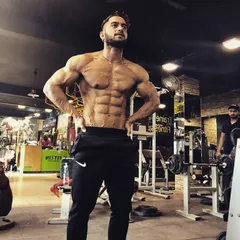 Standing strong in the gym, my second home. This full-body shot displays the V-taper and overall muscular development that is the goal of my transformation programs.