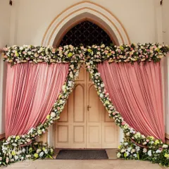 A grand doorway framed with pink drapes and a thick garland of pastel flowers, creating a dramatic and romantic entrance.