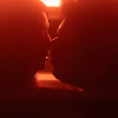 An intensely close-up silhouette in a deep red hue. This abstract and passionate shot focuses on the proximity and connection between the couple, suggesting a deep, unspoken bond.