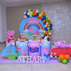 A bright and cheerful Peppa Pig theme for a 4th birthday. This setup includes a large circular backdrop with a rainbow, themed pedestals, a cutout of the iconic red car, and a large number '4'.