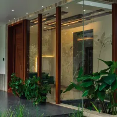 A refined dialogue between materiality and nature. This entrance features a glass wall etched with botanical patterns, with real plants both inside and out, creating a layered, transparent connection to the green surroundings.