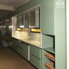 We love playing with color and texture. This modular kitchen features a unique combination of sage green cabinets, a reflective metallic finish, and warm wood accents for a truly bespoke look.
