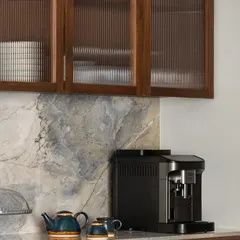 A detail from the West Coast Residence kitchen, where fluted glass cabinet doors and a beautiful marble backsplash add texture and refinement. The space is designed to be both a functional work area and a beautiful part of the home.
