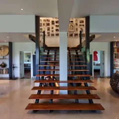 The symmetrical twin staircases at our Aishbagh holiday home, crafted from industrial metal girders and teak treads. This central architectural feature connects the home's private spaces while creating a powerful visual story of movement and memory.