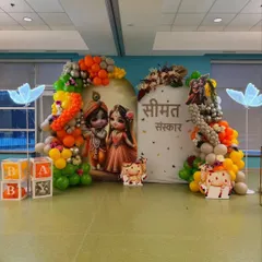 A full setup for a 'Seemant Sanskar' ceremony, featuring Krishna and Radha cutouts, 'BABY' blocks, and colorful balloon arrangements.