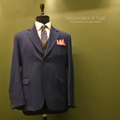 A classic navy pinstripe suit, displayed on a mannequin to show its structure and form. This piece represents our commitment to timeless business wear, complete with a coordinated tie and pocket square.