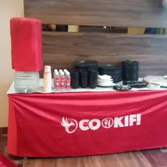 We provide all the essentials for your event. This station includes a water dispenser, plates, bowls, and cutlery, all neatly arranged on our branded table.