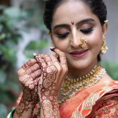 A beautiful close up of a Maharashtrian bride, showing her serene expression, traditional bindi, gold nath, and intricate henna design.