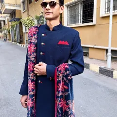 This trendy navy blue Indo-Western sherwani is a versatile choice for any festive occasion. The printed velvet stole adds a luxurious and stylish touch.