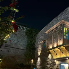 The magical look of a traditional Rajasthani haveli at night in Jodhpur. The warm uplighting on the stone walls and the intricately carved jharokha balcony create a stunning effect that inspires ideas for ambient lighting in home decor.