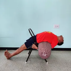 A supported backbend on a chair with a bolster. This setup allows for a deep, passive opening of the chest, which is highly beneficial for improving breathing capacity.