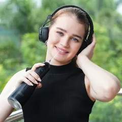 A model uses a black water flosser while listening to music on headphones, associating the product with a relaxed, modern routine.