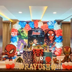 A powerful Spiderman and Avengers theme for Rayush's birthday. The decor features bold red and blue colors, character cutouts, and themed pedestals with spiderwebs and the Hulk's fist.