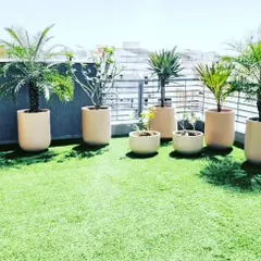 A sunny rooftop terrace with an artificial lawn and a collection of potted plants. This combination gives you a green, maintenance-free lawn plus the flexibility to arrange planters as you like.