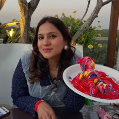 A guest smiling with her red and yellow fluid art teddy bear, made with love at a baby shower. The plastic apron keeps clothes clean while you create.