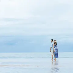 A serene pre-wedding portrait on the beach, using the vastness of the sea and sky to create a minimalist and romantic composition.