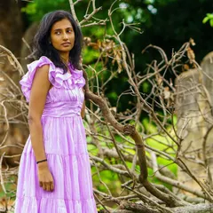 An outdoor portrait set against a rustic, natural background. The soft light and thoughtful expression give this image a serene quality.