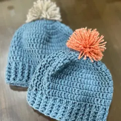 A matching set of baby beanies in a lovely blue, topped with fluffy pom-poms. This set was made for two brothers, sized for 0-6 months and 6-12 months.