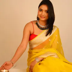 The model's pose and the simple blouse draw focus to the bold, traditional green and gold necklace, making it the centerpiece of the image.