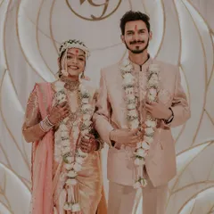 A portrait of the engaged couple, showcasing their matching fresh rose garlands.