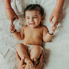 There is nothing more beautiful than a baby's smile. This moment, with mom and dad's hands holding their little one, captures the pure joy and connection that fills a new family. These are the simple, heartfelt memories I aim to preserve for you.