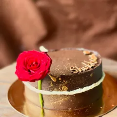 A rich chocolate cake made elegant with a single, perfect red rose and a sprinkle of gold dust.