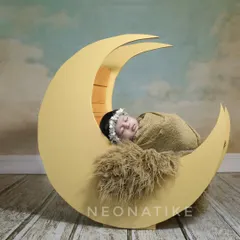 Over the moon for this little one. A simple, elegant shot of a newborn sleeping on a crescent moon prop, perfect for a timeless nursery portrait.