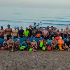 Our Ocean Rangers team, a mix of kids and adults, posing with a rescue surfboard. We are a family of swimmers dedicated to conquering the sea.