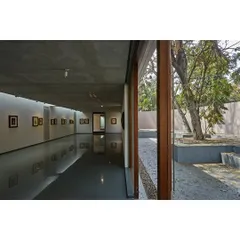A view from the subterranean gallery at the Kasturbhai Lalbhai Museum. A large glass wall opens the underground space to a sunken courtyard, bringing in natural light and connecting the gallery to the landscape above.