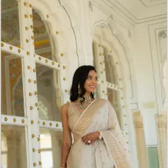 A joyful, candid portrait of Vedika in a beautiful white and gold saree. Her genuine smile and the elegant backdrop of a Rajasthani palace make this a radiant shot.
