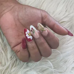 A festive and artistic 3D nail set. This design features a bold red base, a hand-sculpted white flower, painted holly leaves, and a stunning 3D gold bow accent nail.