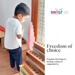A child contemplates the iconic Pink Tower, a sensorial material that teaches size discrimination in three dimensions. This freedom of choice allows children to follow their interests and develop deep concentration.