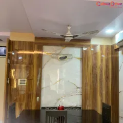 A view of a dining area where we combined a simple false ceiling with a feature wall. The wall combines high-gloss wood-finish panels with a central marble-effect panel, demonstrating our skill in handling multiple materials.