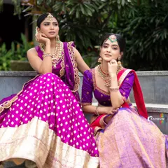 A dual model shoot featuring complementary lehengas in shades of purple and magenta. This type of shot is perfect for showcasing a designer's collection, highlighting how different pieces work together.