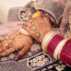 A professional shot capturing the rich, dark stain of the henna against the bride's beautiful jewelry and outfit. The color is consistent and deep across both hands.