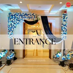 A sophisticated entrance featuring a floral arch of blue and white roses, complemented by deep blue and white drapery for a classic and serene welcome.