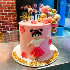 A pretty pink cake for a 6th birthday, featuring a custom girl figurine holding a string of festive balloons.