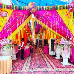 A grand entrance to a housewarming party held in a tent. I used vibrant pink and yellow drapes, hanging flower arrangements, and large decorative vases to create an impressive welcome for guests.