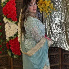 This bride-to-be looks stunning in her pastel green outfit for a pre-wedding event. Her makeup is soft and glowing, with long, wavy hair and a beautiful floral hair accessory.