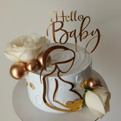 A sophisticated baby shower cake with a gold acrylic topper, fresh white roses, and gold details.