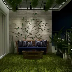 Designed for cozy evenings, this balcony features a comfortable sofa set against a wall with a unique, tree-branch metal art installation. The entire floor is covered with soft artificial grass, and the space is lit to create a dramatic, intimate ambiance against the city skyline.