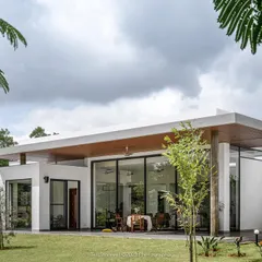 A view of our project, "Nisarg," a contemporary farmhouse near Bengaluru. The design blurs the line between indoors and outdoors, with expansive glass walls that open the living spaces to the garden and the forest beyond.