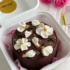 An elegant Belgian chocolate bento cake decorated with delicate, hand-piped white buttercream flowers. The contrast between the dark chocolate and the white florals is timeless.