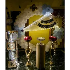We create loving tributes for your special occasions. This home setup features a blue and white balloon arch, elegant brass vases with red roses, and illuminated "LOVE" display boxes for a heartfelt anniversary or birthday celebration.