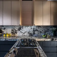 A closer look at the dramatic kitchen in the Grand Utopia penthouse. The combination of a bold marble backsplash, burnished copper cabinetry, and an integrated grill transforms this culinary space into a sculptural showpiece.