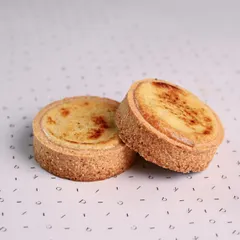 A pair of classic Japanese Cheese Tarts. The tops are lightly brûléed for a slightly caramelized flavor, contrasting with the creamy, melt-in-your-mouth filling.