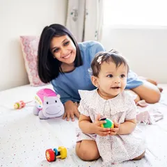 Do you love minimal and candid photoshoots? This mother and baby are enjoying a simple, happy moment on the bed with a few favorite toys. The focus is purely on their connection and joy.