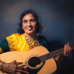 Part of the 'Saris by Mothers of India' series, this image blends tradition with a touch of modern fun. The subject's joyful expression while holding a guitar shows a beautiful, unexpected side of her personality.