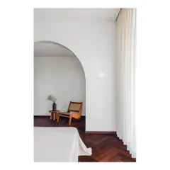 A master bedroom designed as a minimalist refuge. The simple archway creates a gentle transition into a quiet reading nook, demonstrating my belief that homes should provide spaces for peace and silence away from a frenetic world.